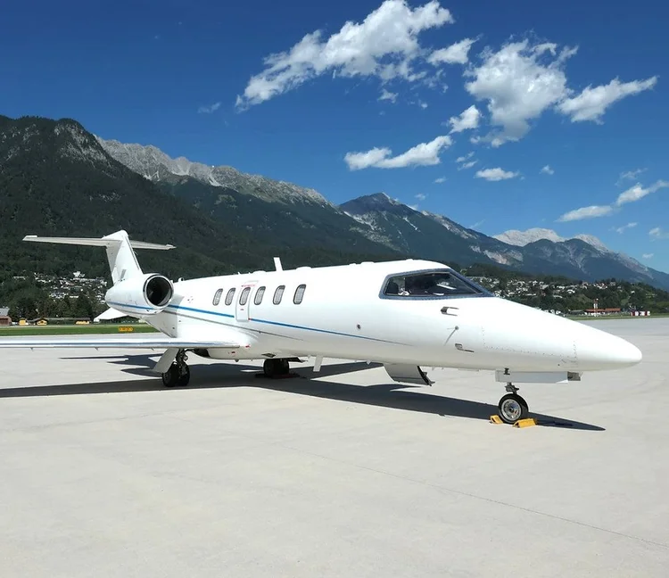 Learjet da Omni na pista com montanhas ao fundo